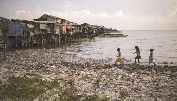 A recent photo shows children walking along a garbage-filled bay in Manila.