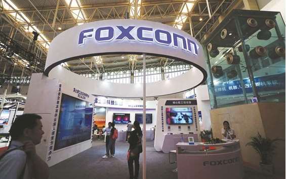 Visitors are seen at a Foxconn booth at the World Intelligence Congress in Tianjin, China. The Taiwanese contract manufacturer that rose to global prominence as the manufacturer of the Apple iPhone, is trying to reinvent itself as smartphone sales plateau and Apple diversifies its supplier base.
