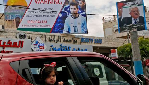 A poster erected on a main street in the West Bank town of Hebron next to a portrait of the Palestinian president Mahmud Abbas (R), denouncing the upcoming friendly football match between Argentina and Israel and calling Argentina's star Lionel Messi (portrait) to boycott the match.