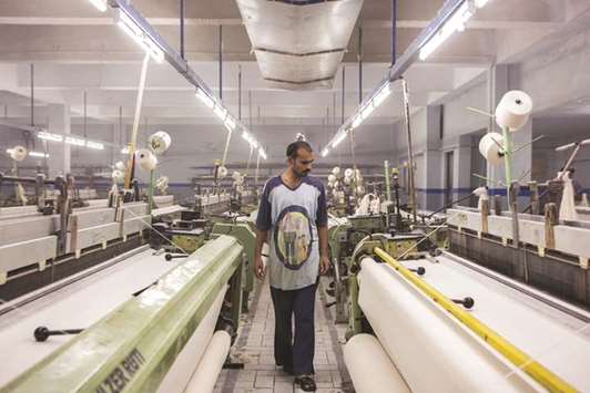 A worker inspects fabric on looms at a textile manufacturer in Karachi. The World Bank has forecast Pakistanu2019s economic growth in next fiscal year to slow down owing to higher than expected oil prices.