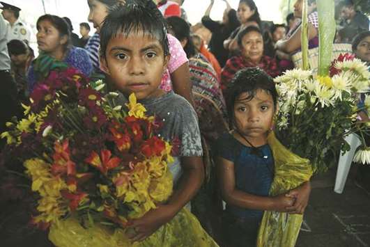Children hold bunches of flowers during the funeral of 20-year-old Erick Rivas, a victim of the Fuego volcano eruption, in Alotenango municipality, Sacatepequez, about 65km southwest of Guatemala City on Wednesday.