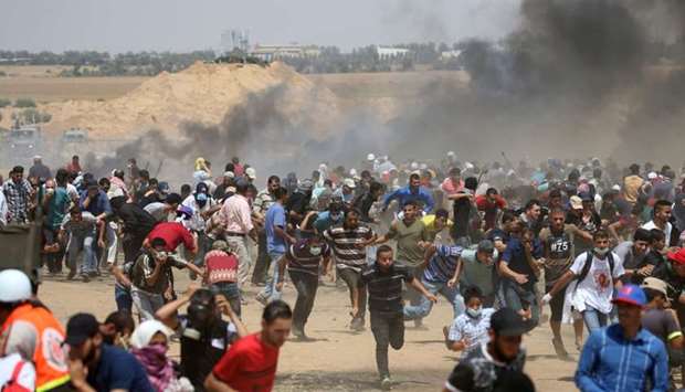 Palestinian demonstrators run for cover from Israeli gunfire during a protest marking al-Quds Day, (Jerusalem Day), at the Israel-Gaza border in the southern Gaza Strip