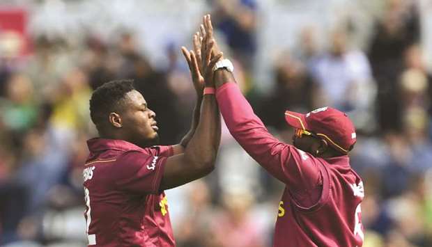West Indiesu2019 Oshane Thomas (left) celebrates with teammate Andre Russell a taking a wicket during the 2019 ICC Cricket World Cup match against Australia in Nottingham, England, on Thursday. (AFP)
