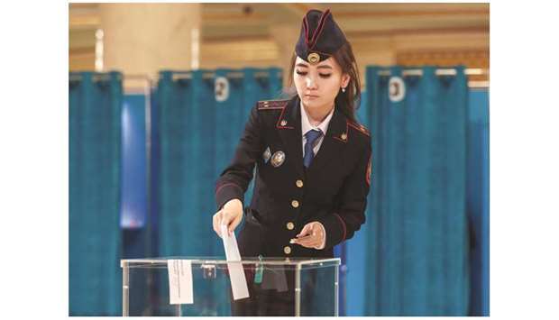 An officer casts her ballot at a polling station in Nur-Sultan during the  presidential election.