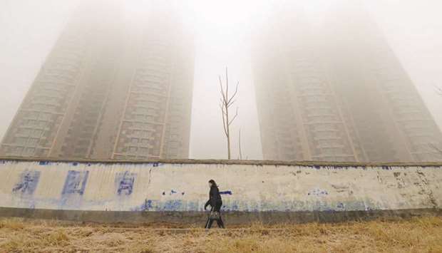 A woman wearing a mask walks past buildings on a polluted day in Handan, Hebei province, China, in this January 12, 2019 photograph.