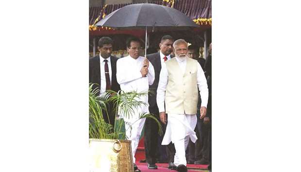 Indian Prime Minister Narendra Modi, right, and Sri Lankan President Maithripala Sirisena walk under an umbrella as they attend a welcoming ceremony for Modi at the Presidential Secretariat in Colombo yesterday.