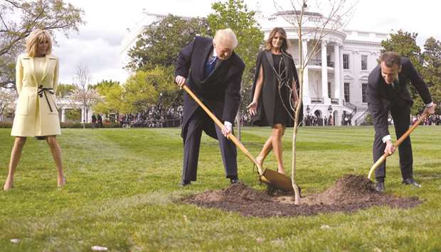 This April 23, 2018, file photo shows US President Donald Trump and French President Emmanuel Macron planting a tree on the grounds of the White House in Washington, DC as Trumpu2019s wife Melania and Macronu2019s wife Brigitte look on.