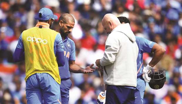 Indiau2019s Shikhar Dhawan (second from left) receives medical treatment after being hit on the hand with a ball during the 2019 ICC Cricket World Cup match against Australia in London on Sunday. (AFP)