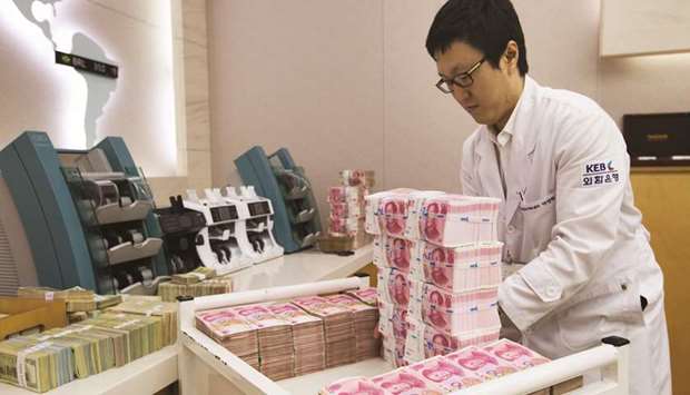An employee arranges yuan banknotes at the Korea Exchange Bank headquarters in Seoul. Chinau2019s central bank will sell yuan-denominated bills in Hong Kong in late June, in a move some market analysts believe is aimed at preventing the yuan currency from declining further.