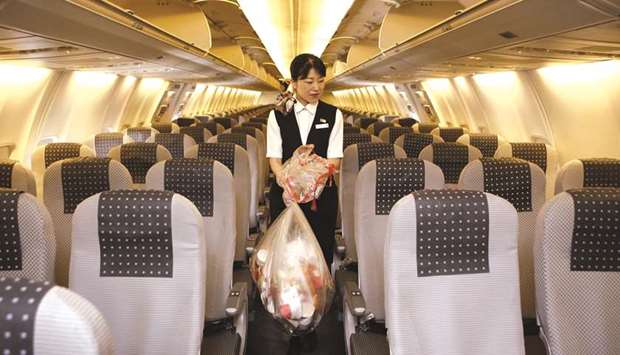 A cabin attendant carries bags of trash in the cabin of a Japan Airlines airplane at Haneda Airport in Tokyo (file). An industry research carried out at Londonu2019s Heathrow airport over a period of two years has highlighted the pressing need for tackling cabin waste issues, in particular the wastage from inflight meal services.