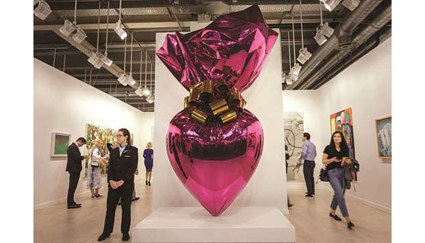 Visitors stand next to an artwork by Jeff Koons, entitled Sacred Heart (Magenta/Gold) at the Gagosian gallery exhibition space during a preview day of Art Basel, the worldu2019s premier modern and contemporary art fair, on June 12, 2019 in Basel. Thousand of art collectors, art dealers, artists, curators and art lovers are expected to attend the annual meeting place of the art community with 290 of the worldu2019s leading galleries showing the works of more than 4,000 artists.