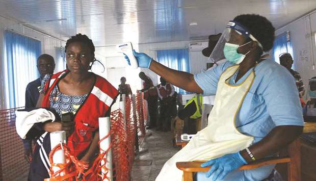 A health worker checks the temperature of a woman as she crosses the border point separating Uganda and the Democratic Republic of Congo, as part of the Ebola screening at the computerised Mpondwe Health Screening Facility in Mpondwe, Uganda.