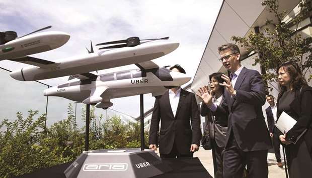 Barney Harford, chief operating officer of Uber Technologies Inc (second from right), speaks to an attendee next to a scaled model of the companyu2019s eCRM-003, an electric vertical take-off and landing jet, during the Uber Elevated Asia Pacific Expo event in Tokyo, Japan, on August 30, 2018. Uber is now betting that what the industry calls u201curban air mobilityu201d will become a major part of its transportation business in the future.