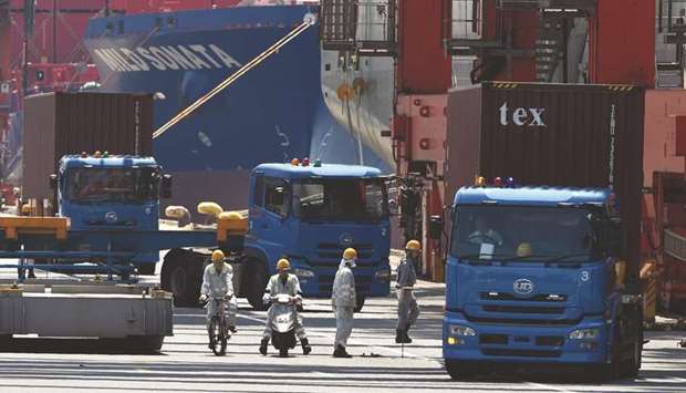 Trucks are seen transporting containers from a pier in Tokyou2019s port. Japanu2019s exports likely fell at a faster pace in May, down for the sixth straight month, as the US-China trade war takes a toll on the economy, a Reuters poll showed yesterday.