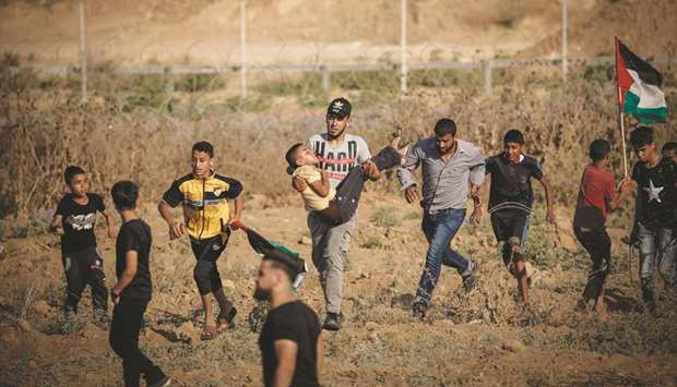 Palestinians evacuate a wounded demonstrator during clashes with Israeli forces near the fence along the border near Bureij in the central Gaza Strip, yesterday.