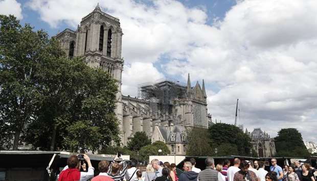 People walk along the banks of the River Seine past the Notre-Dame de Paris cathedral.