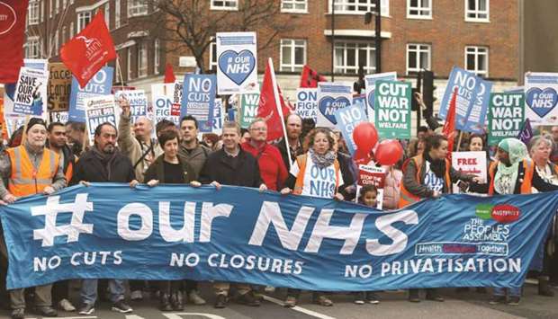 FILE PHOTO: People taking part in a demonstration to demand more funding for Britainu2019s National Health Service (NHS) hold a banner, in London.