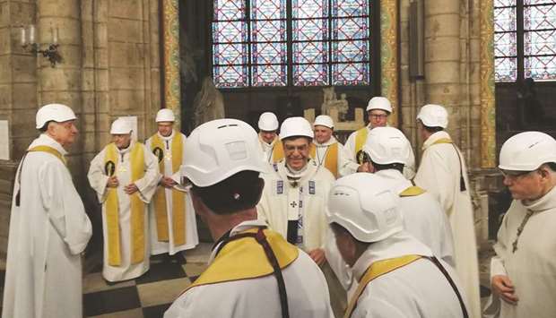 The Archbishop of Paris Michel Aupetit (centre) greets other members of the clergy following the first mass in a side chapel, two months to the day after a devastating fire engulfed the Notre-Dame de Paris cathedral.
