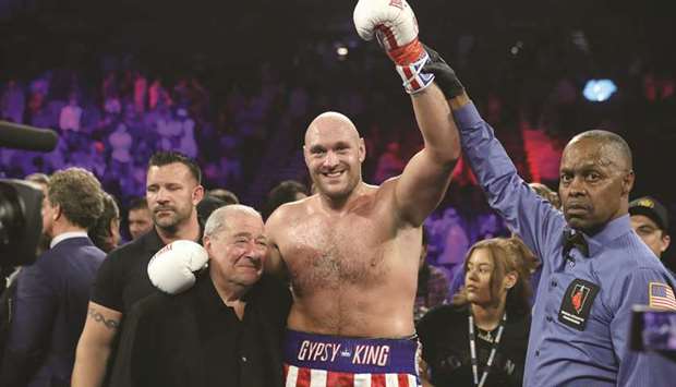 Tyson Fury (C) poses with boxing promoter Bob Arum (L) and referee Kenny Bayless after defeating Tom Schwarz (bottom) during their heavyweight fight at MGM Grand  Garden Arena in Las Vegas, Nevada. Fury won with a second-round TKO.