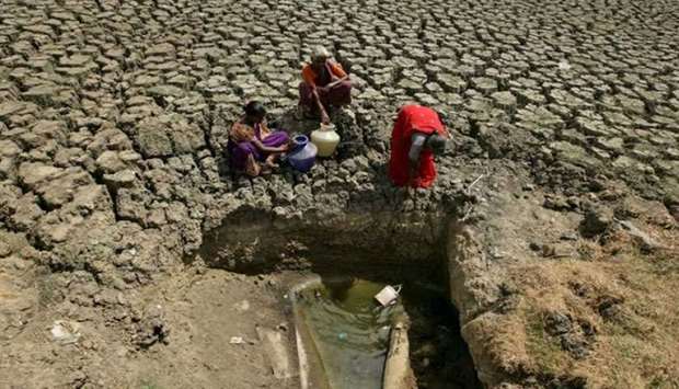 Women fetch water from an opening made by residents at a dried-up lake in India
