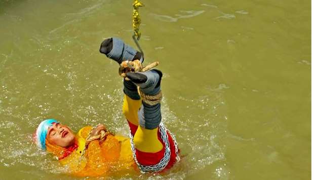 Indian stuntman Chanchal Lahiri, known by his stage name ,Jadugar Mandrake,, is lowered into the Ganges river, while tied up with steel chains and ropes in Kolkata on June 16, 2019