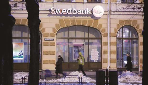 Pedestrians walk through snow past a Swedbank bank branch in Riga, Latvia (file).