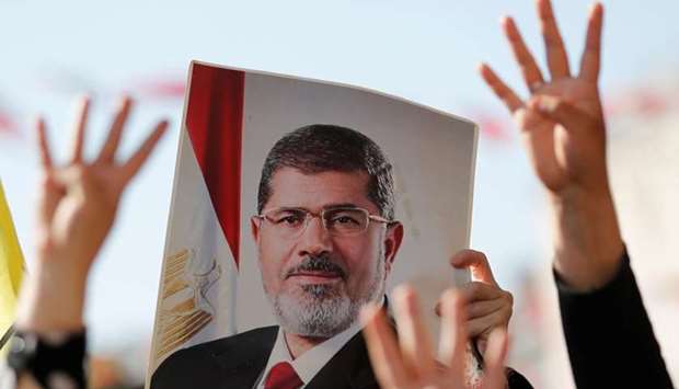People flash Rabia signs as they hold a picture of former Egyptian president Mohamed Mursi during a symbolic funeral prayer at the courtyard of Fatih Mosque in Istanbul