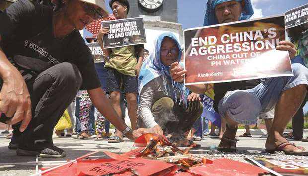 Activists burn Chinese flags and display anti-China placards during a protest at a park in Manila, yesterday, after a Chinese vessel last week collided with a Philippine fishing boat which sank in the disputed South China Sea and sailed away sparking outrage.