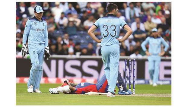 Englandu2019s Mark Wood (C) walks to Afghanistanu2019s Hashmatullah Shahidi after the ball hit his helmet during their match at Old Trafford in Manchester on Tuesday.