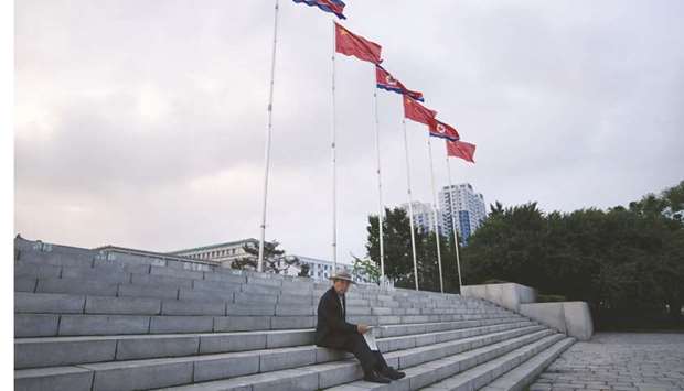 A man sits before North Korean and Chinese flags flying on Kim Il-sung square in Pyongyang yesterday.