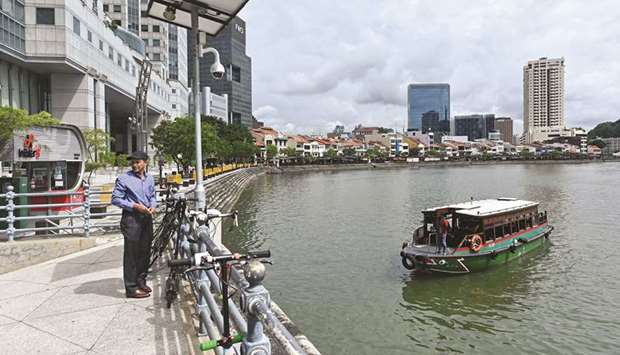 A man stands near a surveillance camera at the financial district in Singapore.