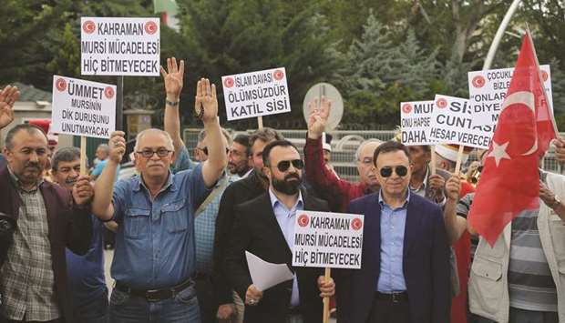 People hold placards reading u2018Hero Mursi, his struggle will never endu2019 or u2018Junta, will accountu2019 and flash the four-finger sign known as Rabaa as they protest in front of the Egyptian embassy in Ankara yesterday.