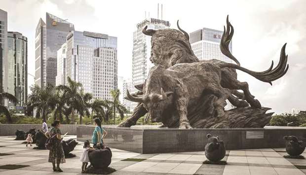People stand in front of a sculpture of bulls at the entrance to the Shenzhen Stock Exchange building in China. The Shanghai and Shenzhen stock exchanges have been inundated with investor queries about spinoffs on the new Nasdaq-style tech board, where the first listing is expected in the next two months.