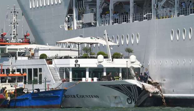 Rescuers stand onboard the damaged River Countess tourist boat after it was hit early on June 2, 2019 by the MSC Opera cruise ship (Rear) that lost control as it was coming in to dock in Venice, Italy.