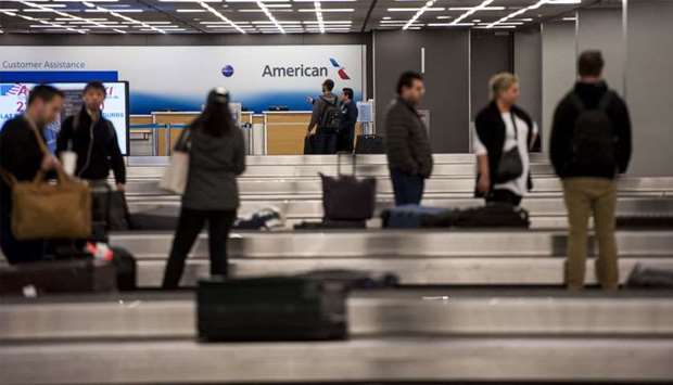 Travelers await their baggage at the claim area at O'Hare International Airport in Chicago, Illinois