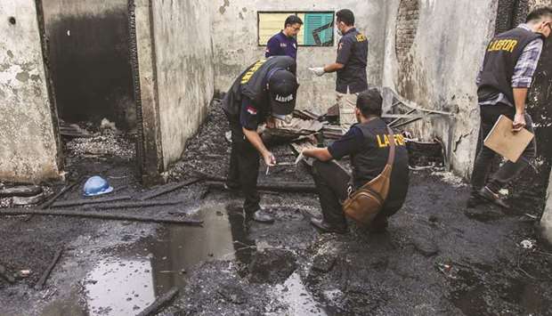 Investigators work on the scene of a burnt-out house that doubled as a matchstick factory in Binjai yesterday following a fire on the premises that killed at least 30.