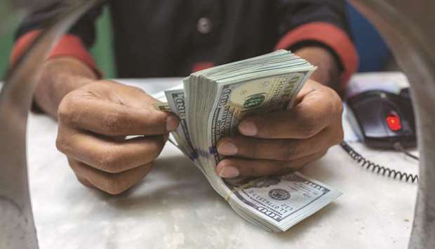 A teller counts US hundred dollar bills inside a currency exchange store in Karachi. Currency exchange rate remained relatively steady during the week ended on Friday in Pakistan but analysts fear the stability may be short-lived as foreign exchange reserves continue to decline.