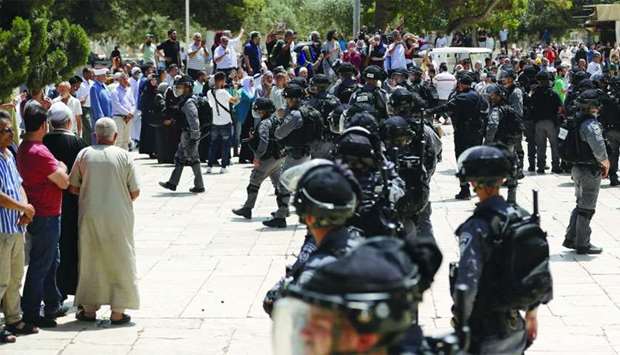 Israeli security forces stand guard in front of a group of Palestinians at the Al Aqsa Mosque compound