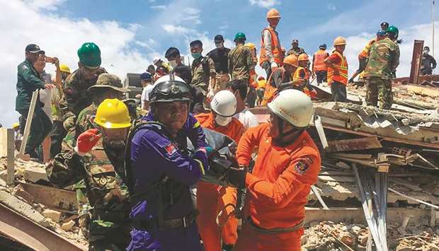 Rescue workers remove a victim from the debris after an under-construction building collapsed in Sihanoukville yesterday.
