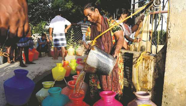 A local resident pours water collected from a community well in Chennai.