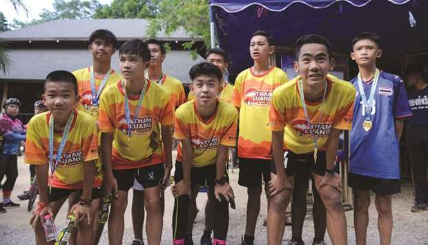 Members of the u201cWild Boarsu201d football team and their coach pose at the visitor centre for the Tham Luang cave, where the 12 boys and their coach were trapped last year, before participating in a marathon in the Mae Sai district of Chiang Rai province, yesterday.