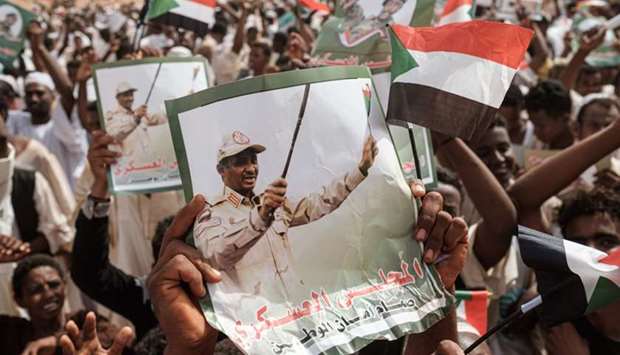Supporters hold portraits of Mohamed Hamdan Dagalo (R), known as Himediti, deputy head of Sudan's ruling Transitional Military Council (TMC) and commander of the Rapid Support Forces (RSF) paramilitaries, before a rally in the village of Abraq, about 60 kilometers northwest of Khartoum