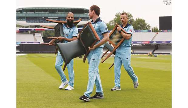 (From left) Englandu2019s Moeen Ali, Eoin Morgan and Tom Curran carry chairs after a team group photo during nets at Lordu2019s in London yesterday. (Reuters)