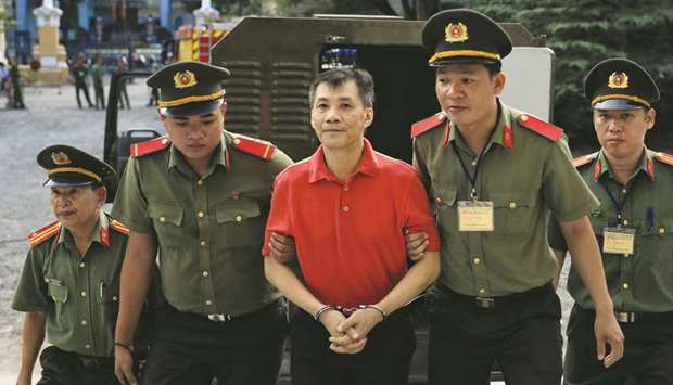 US citizen Michael Nguyen is escorted by policemen before his trial at a court in Ho Chi Minh City yesterday.