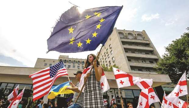 Protesters waive the EU, Georgian and American flags during their motorcade rally yesterday in Tbilisi. The head of Georgiau2019s ruling party has announced sweeping electoral reforms in a bid to appease protesters after days of demonstrations gripped the capital Tbilisi.