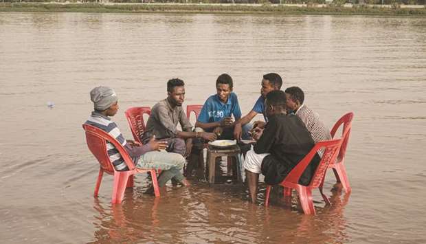 Sudanese men share a meal in the shallows waters of the Tuti island, where the Blue and White Nile merge in Khartoum, yesterday.