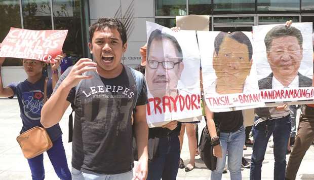 An activist (second left) speaks next to portraits of  President Rodrigo Duterte and Chinau2019s President Xi Jinping during a protest in front of the Chinese consulate in Manila, yesterday, after a Chinese vessel last week collided with a Philippine fishing boat which sank in the disputed South China Sea and sailed away sparking outrage.