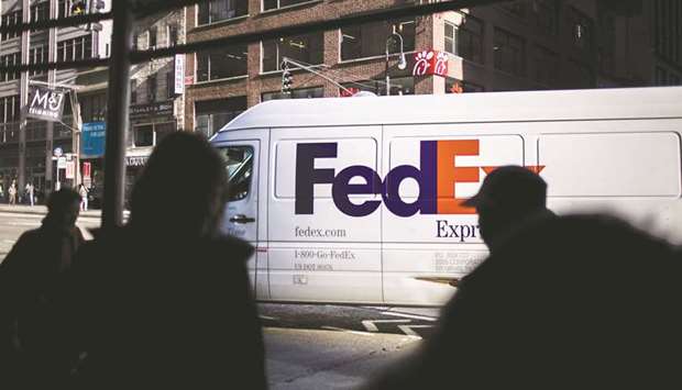 The silhouettes of pedestrians are seen walking past a FedEx Corp vehicle in the Midtown neighbourhood of New York.