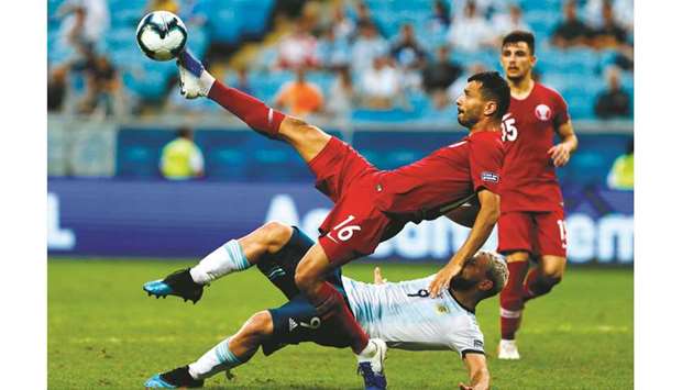 Qataru2019s Boualem Khoukhi (top) and Argentinau2019s Sergio Aguero struggle for the ball during the Copa America match at the Gremio Arena in Porto Alegre, Brazil, on Sunday. (AFP)
