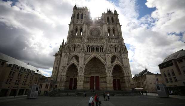 People stand in front of the Cathedral of Notre-Dame d'Amiens in Amiens, France